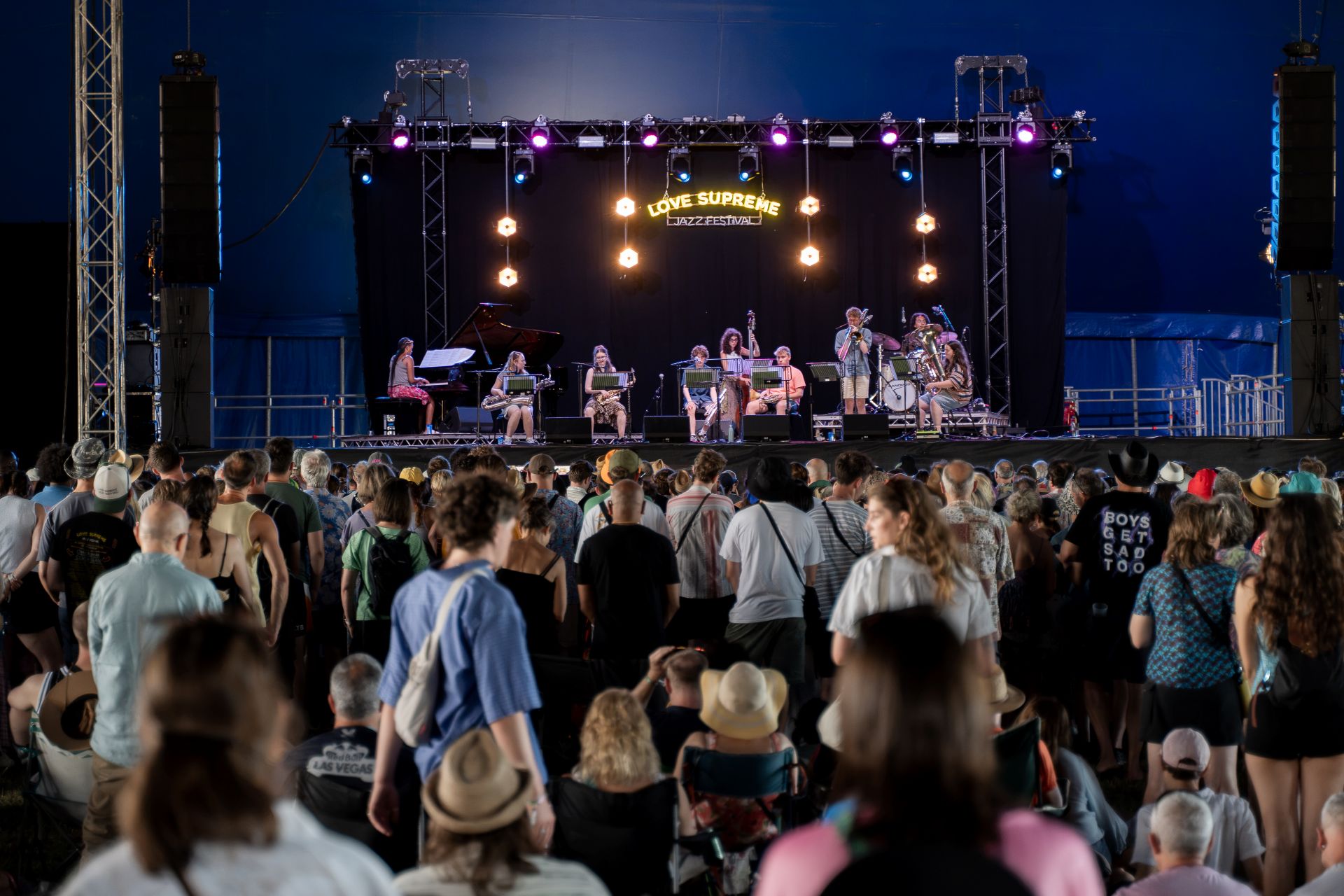 A large crowd in front of a stage at a music festival