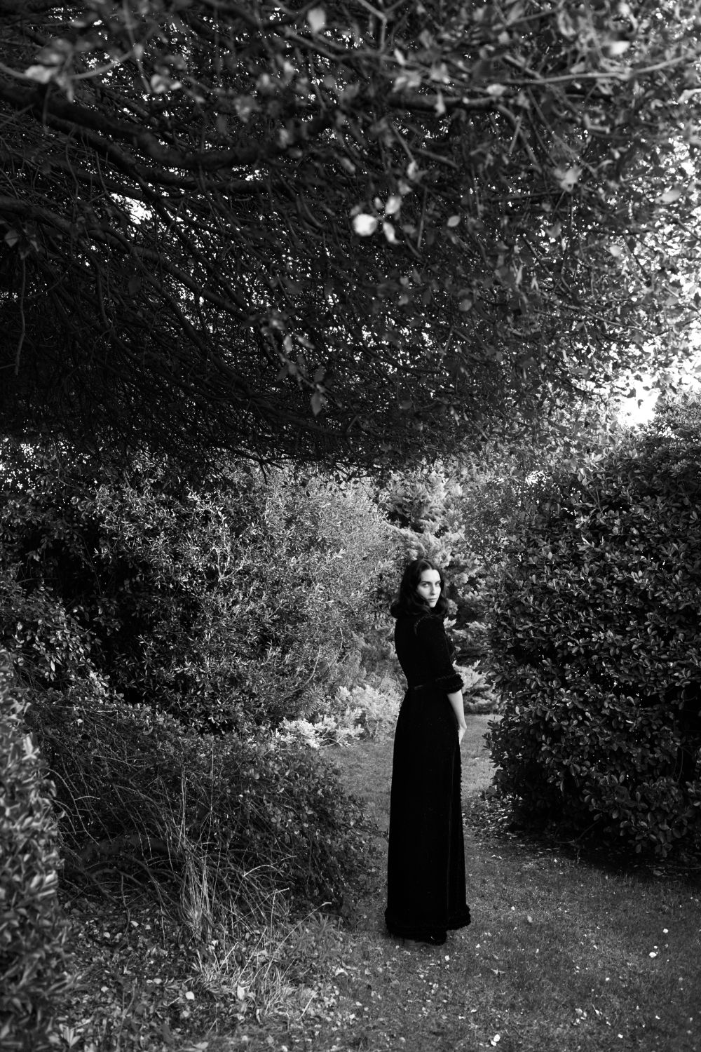 Susie Cave standing on grass surrounded by trees and bushes