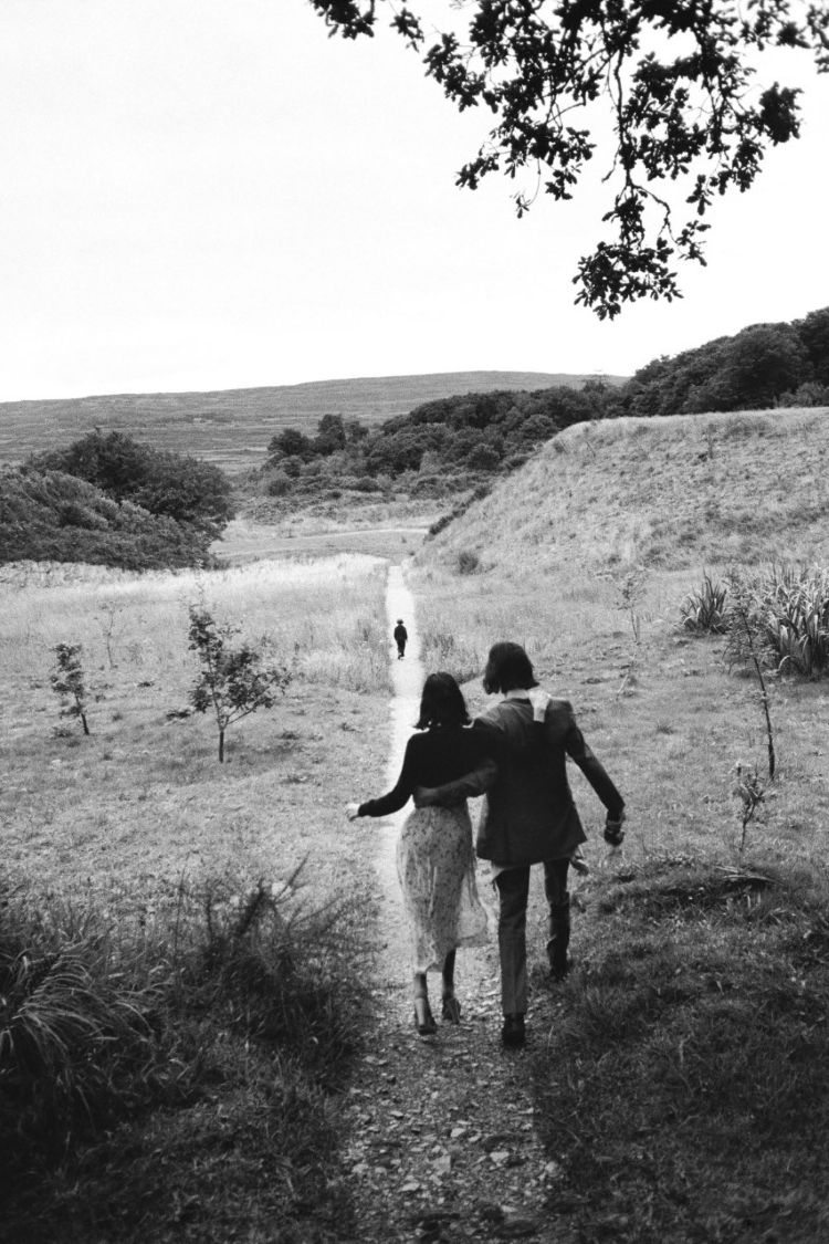 Susie and Nick embracing on a walk with a child running into the distance