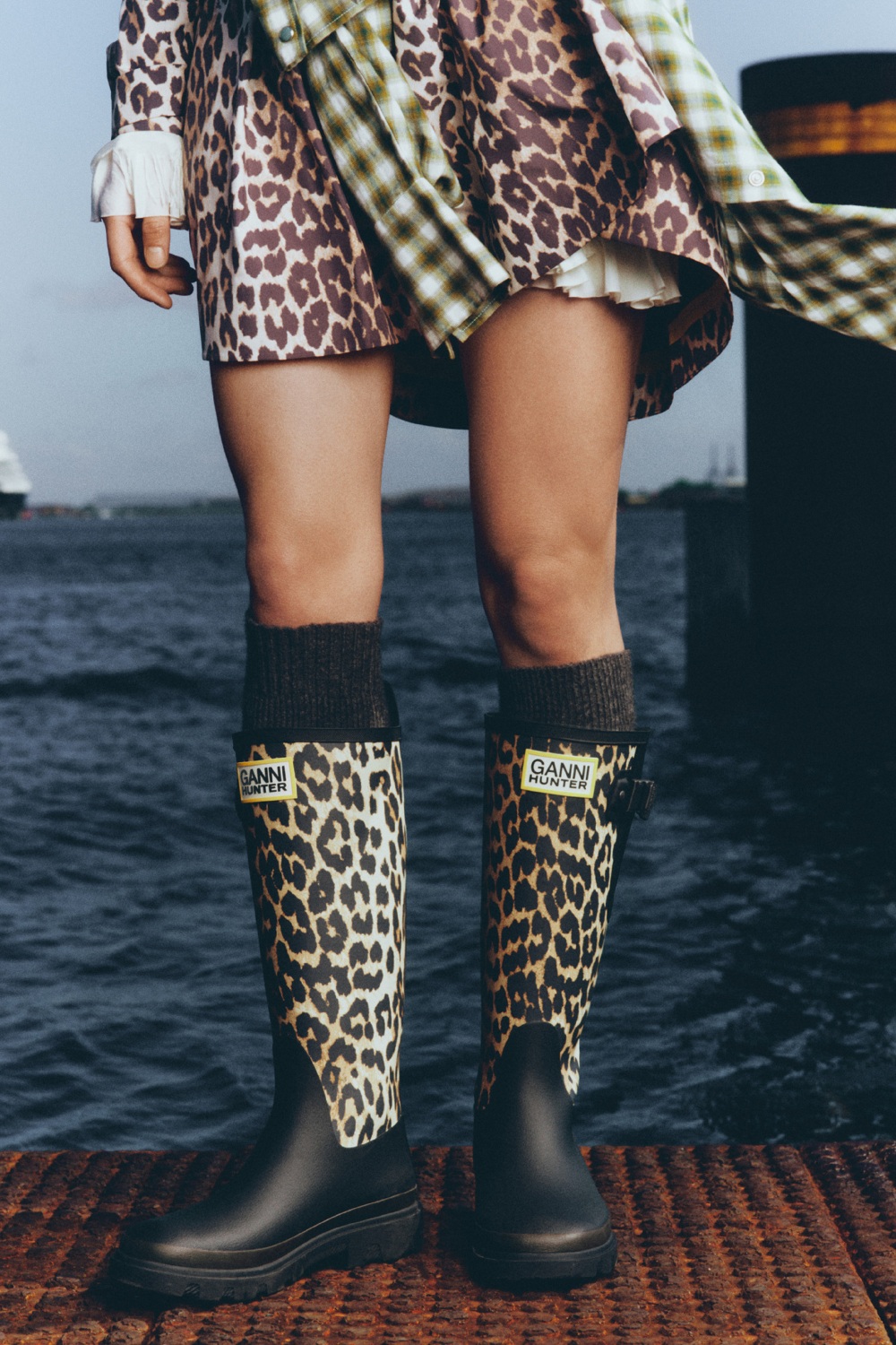 Woman wearing GANNI x Hunter collection boots and poncho