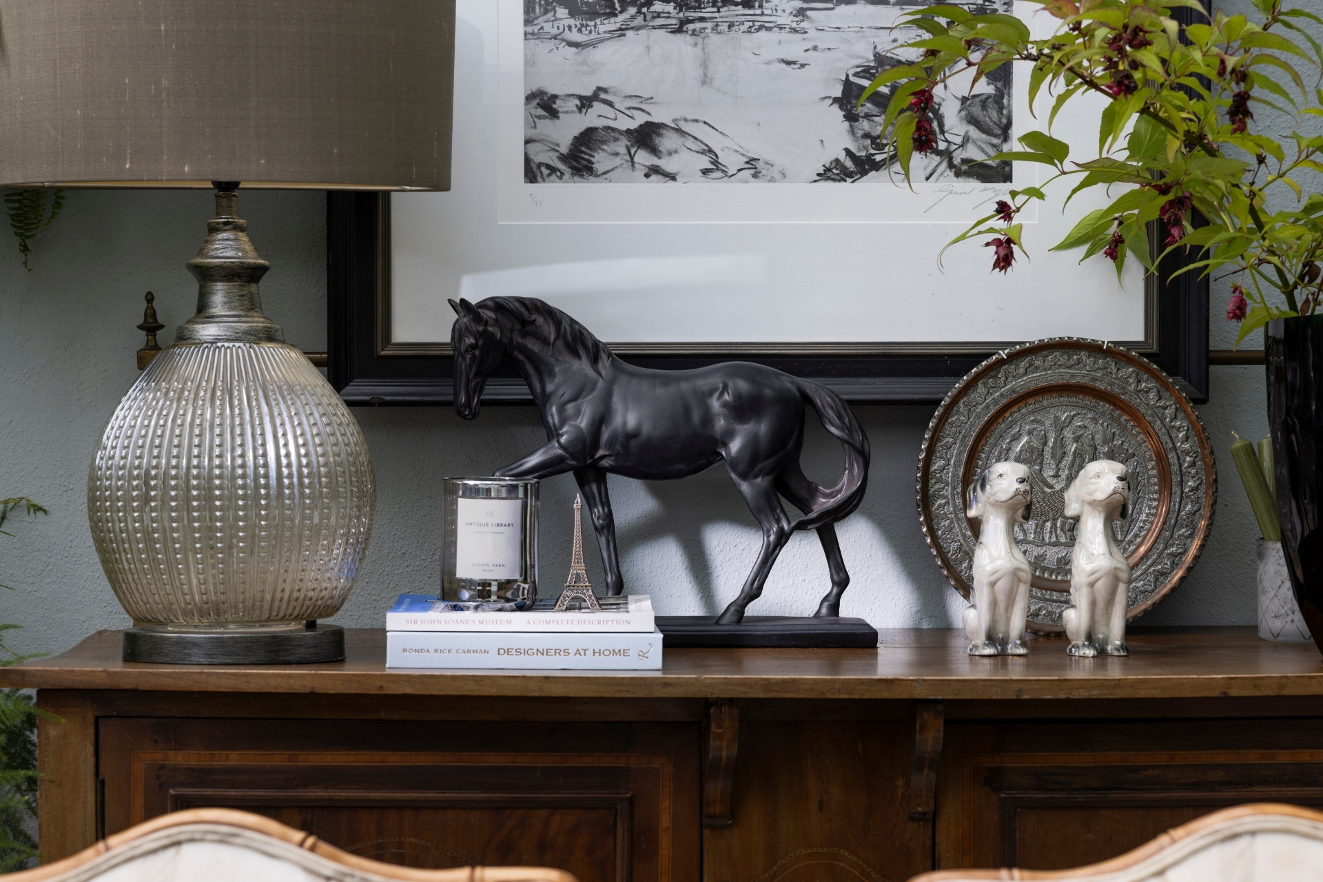 Mantle with lamps, books, sculptures and artworks - located in Sara Cosgrove's conservatory
