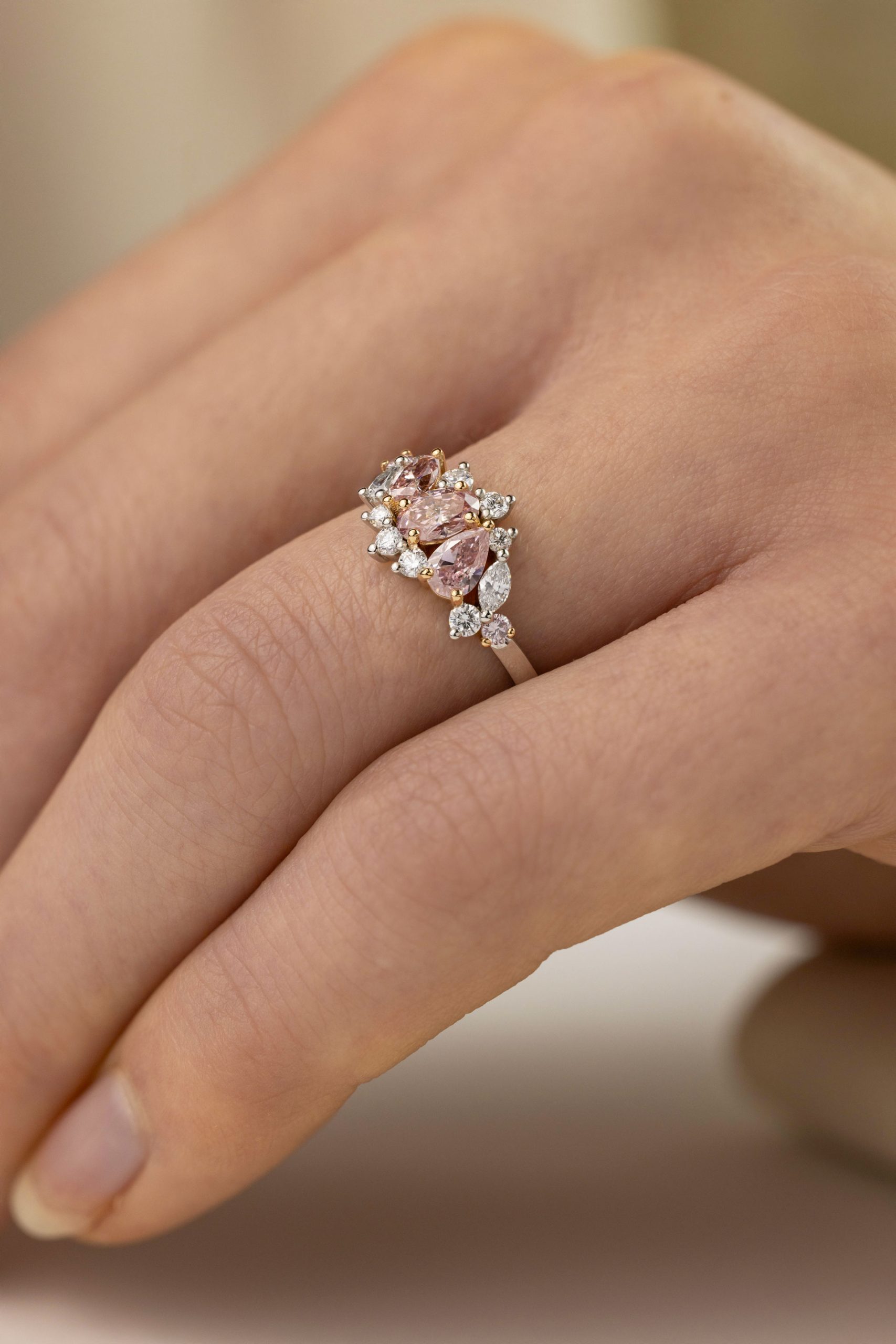 An assymetrical pink diamond ring on a finger