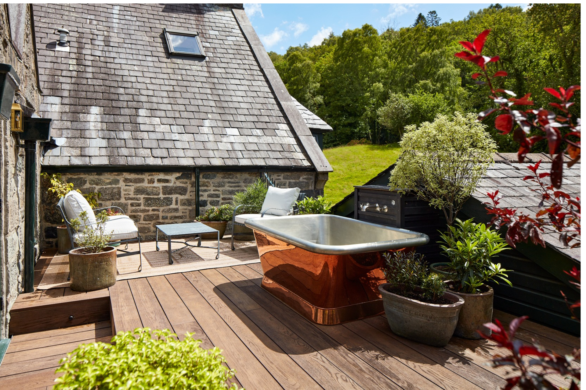 An outdoor terrace with a copper bathtub at Penmaenuchaf hotel